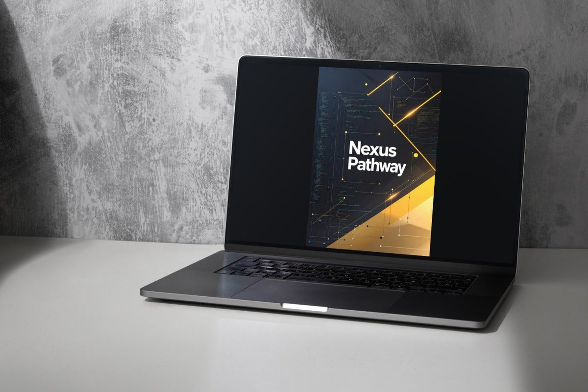 A dark gray laptop sits open on a white surface against a textured gray wall, with the screen displaying a graphic that reads 'Nexus Pathway'.